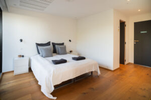 Lys og moderne soveværelse med dobbeltseng, hvide vægge og trægulv. Perfekt til fremvisning af udlejningsboliger på Airbnb eller andre platforme. Fotograferet af Weigang Fotografi, ekspert i bolig- og interiørfotografering i København.