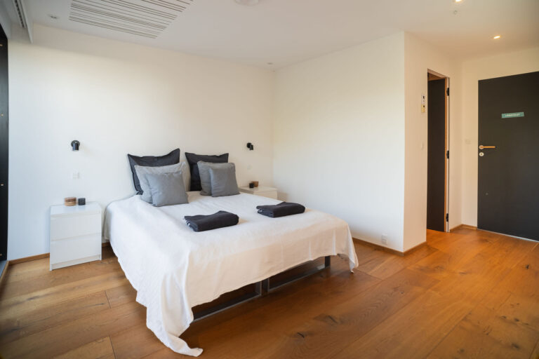 Lys og moderne soveværelse med dobbeltseng, hvide vægge og trægulv. Perfekt til fremvisning af udlejningsboliger på Airbnb eller andre platforme. Fotograferet af Weigang Fotografi, ekspert i bolig- og interiørfotografering i København.