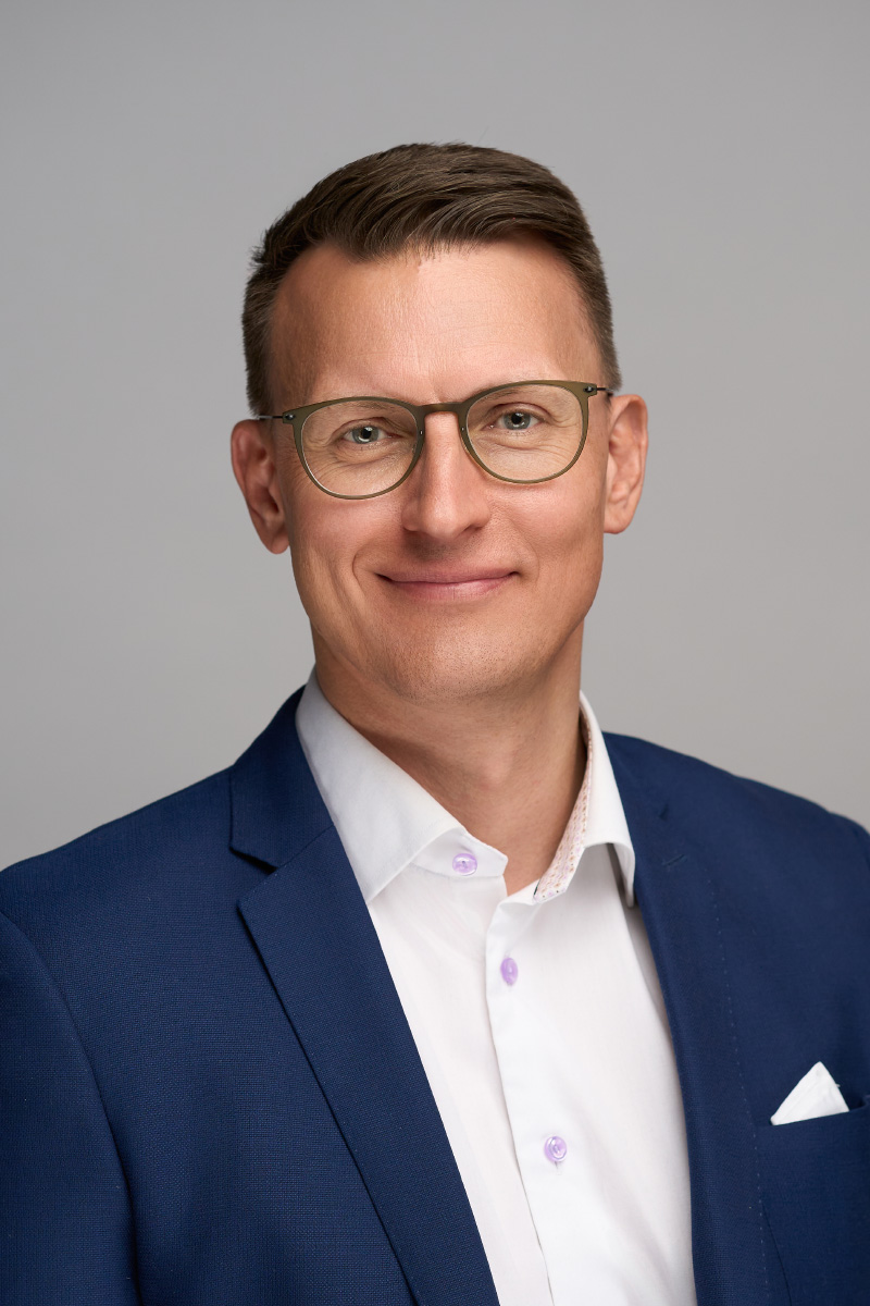 Professionelt headshot af mand med briller i blå blazer og hvid skjorte, ideelt til LinkedIn og erhvervsprofiler. Portrætfotografering fra Weigang Fotografi i København, specialiseret i professionelle medarbejderportrætter.